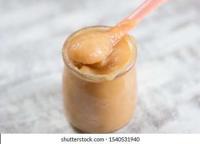 Apple Sauce In Glass Jar And Spoon On White Background