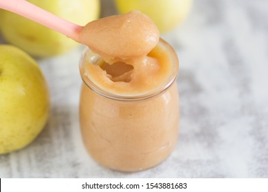 Apple Sauce In Glass Jar And Spoon On White Background