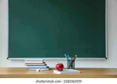 Apple with school books and pen cup on table near chalkboard - Powered by Shutterstock