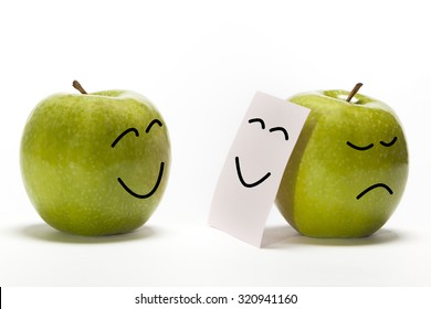 An apple smiling to other one, that is concealing its sadness behind a smiley mask