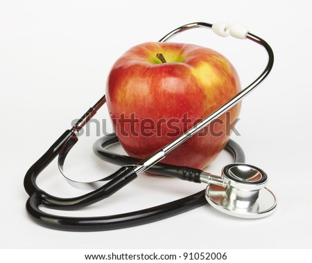 Apple and stethoscope on white background