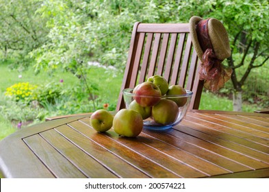 Apple Tree Fruits In Glass Dish On Bower Table In Garden.  