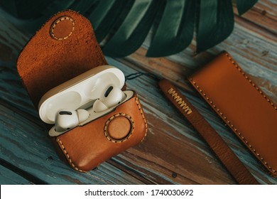 Apple wireless earphone in leather case on wooden background
