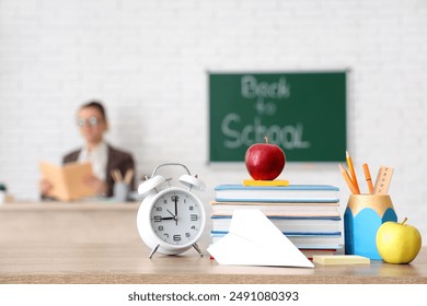 Apples, books, alarm clock and paper plane on desk in classroom. Back to school concept - Powered by Shutterstock