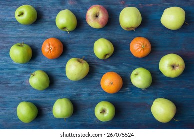 Apples and oranges on old wooden background