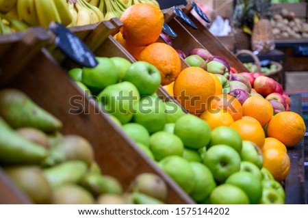 Apples, oranges, pears and bananas on display and ready for sale at a fruit and veg stall in Borough Market, London.