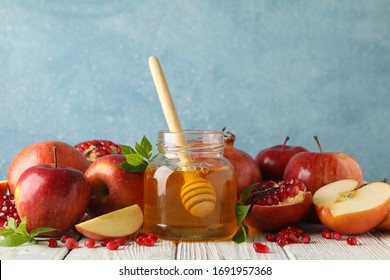 Apples, pomegranate and honey on wooden table, close up