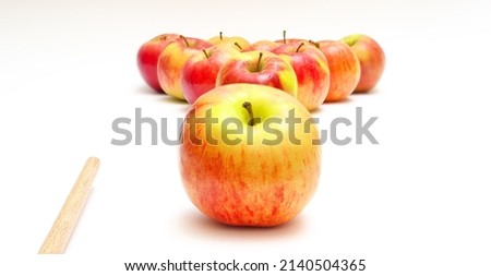 Apples in a triangle, one apple separately and a cue on a white background. Emulation of billiards. Selective focus.