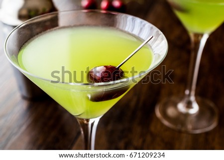 Appletini Cocktail with cherry on wooden surface.