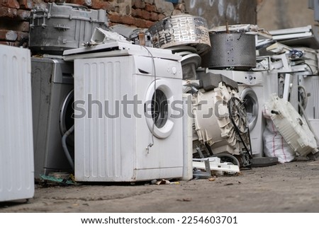 Appliance recycling concept. Old used washing machines on street. E-waste at landfill, local scrap yard