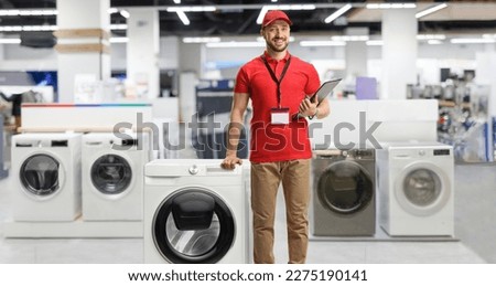 Appliance sales associate leaning on a washing machine inside a shop