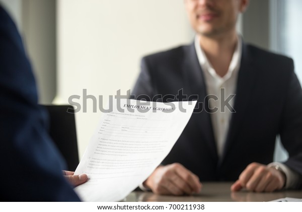 Applicant holding employment agreement, considering\
work terms, reading position duties before signing official labor\
contract, successful vacancy candidate getting hired, job\
placement, close up