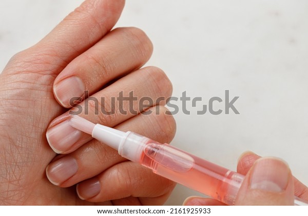 Application of cuticle oil. Nail Care
and manicure. Natural woman's nails. White
background.