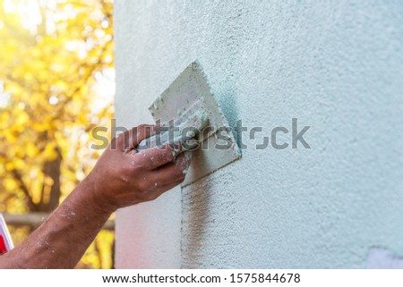 Application Of Facade Plaster,Worker Plastering The Facade Of The Building, Close-Up.