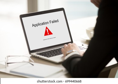 Application failed, businessman having problem with laptop, bad software failure on screen, broken computer stopped working in office, hanging pc caused system crash error message, close up rear view