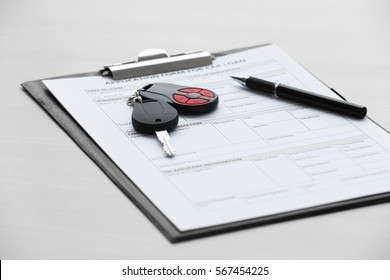 Application form for car loan, pen and key on wooden table, close up view