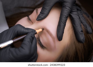 Application of markings with a pencil on the contour of the eyebrows before the procedure of permanent makeup. PMU Procedure, Permanent Eyebrow Makeup.