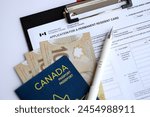 Application for permanent resident card on table with pen and canadian passport with money close up