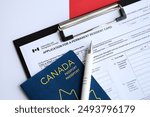 Application for permanent resident card on table with pen and canadian passport close up