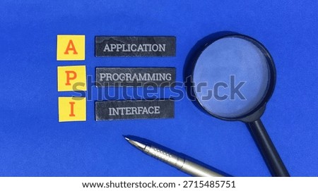 Application programming interface acronym spelled out using blocks on a vibrant blue surface symbolizes the examination of software integration concepts with a magnifying glass.