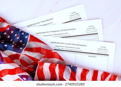 Application various forms for immigration are placed on citizenship immigration table next to an American flag.