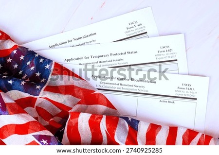 Application various forms for immigration are placed on citizenship immigration table next to an American flag.