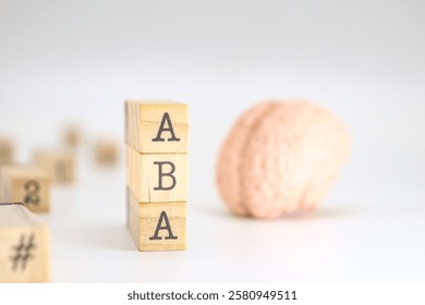 Applied behavior analysis acronym. ABA written on wooden cubes isolated with a figure of a brain on white background with space for text.