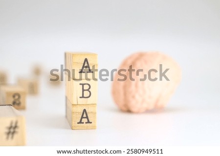 Applied behavior analysis acronym. ABA written on wooden cubes isolated with a figure of a brain on white background with space for text.