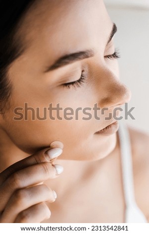 Applying acne round patch on cheek of girl close-up. Young woman using acne patches for treatment of pimple and rosacea. Facial rejuvenation cleansing cosmetology