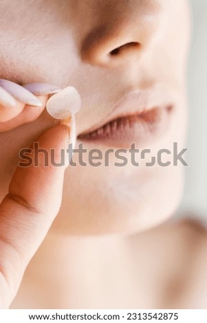 Applying acne round patch on cheek of girl close-up. Young woman using acne patches for treatment of pimple and rosacea. Facial rejuvenation cleansing cosmetology
