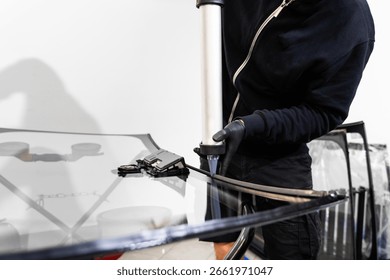 Applying adhesive to a car windshield using a caulking gun. Urethane caulking gun applies flexible adhesive, forming a watertight seal at car windshield replacement