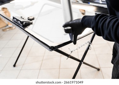 Applying adhesive to a car windshield using a caulking gun. Urethane caulking gun applies flexible adhesive, forming a watertight seal at car windshield replacement