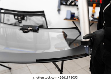 Applying adhesive to a car windshield using a caulking gun. Urethane caulking gun applies flexible adhesive, forming a watertight seal at car windshield replacement