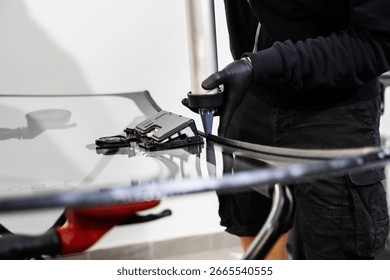 Applying adhesive to a car windshield using a caulking gun. Urethane caulking gun applies flexible adhesive, forming a watertight seal at car windshield replacement