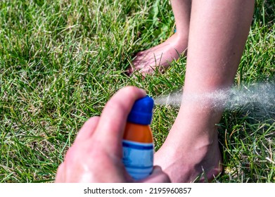 Applying An Aerosol Spray Sunscreen To A Young Child In The Summer. 