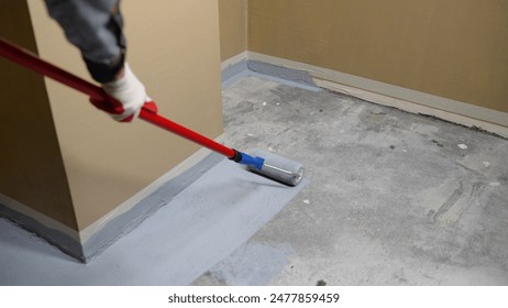 Applying an anti-slip layer to the floor of an underground parking lot. Paint the floor using a roller with a long handle. Painting the floor with a roller, repairing the floor.