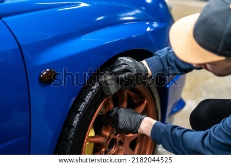 applying black car tire polish on the wheels