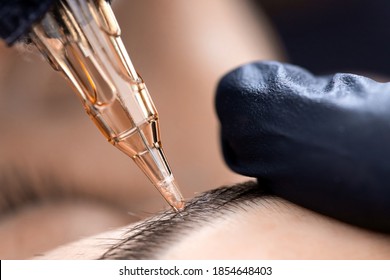 Applying Black Pigment With Tattoo Machine On Woman Eyebrows, Permanent Makeup In Beauty Salon.