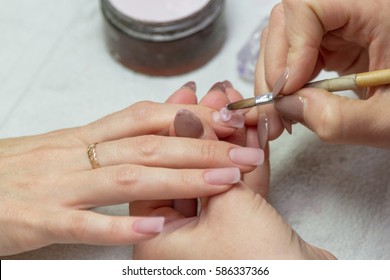 applying a brush on acrylic nails in the salon - Shutterstock ID 586337366