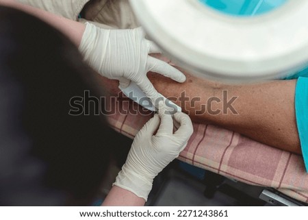 Applying clean dressing to a disinfected dog bite wound on the forearm of a patient at a bite center or local clinic.