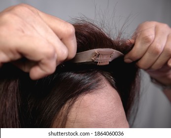Application d'une coupe de cheveux sur les cheveux et le cuir chevelu naturels d'une femme. Couvrant l'éclaircie des cheveux sur la couronne ou la partie avant de la tête ou ajoutant du volume. Le clip de perruque avant est visible.