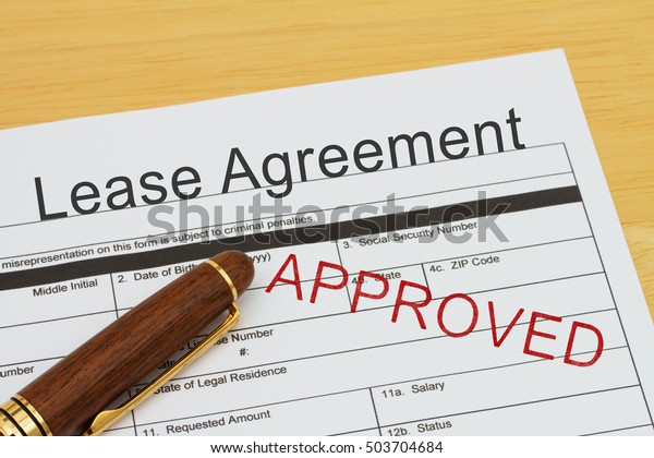 Applying for\
a Lease Agreement Approved, Lease Agreement application form with a\
pen on a desk with an approved\
stamp