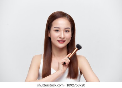 Applying Make Up. Smiling Attractive Young Woman Holding Brush Near Face Looking At Camera Isolated Over Studio Wall