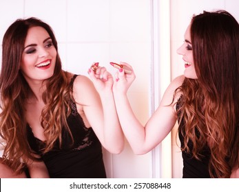 Applying makeup funny idea. Young pretty woman drawing heart sign symbol on mirror in bathroom.