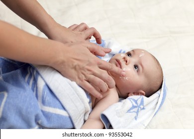 Applying Moisturizing Cream On Face Of Baby After Bath