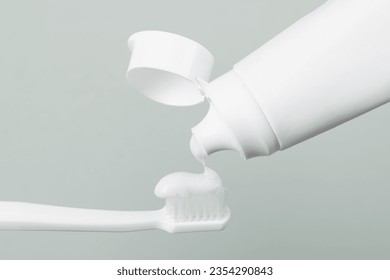 Applying paste on toothbrush against grey background, closeup