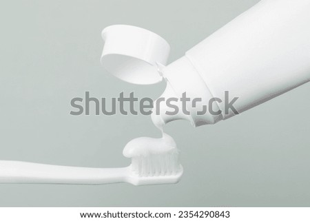 Applying paste on toothbrush against grey background, closeup