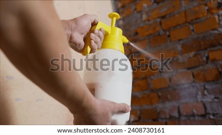 Applying primer using a spray bottle to a brick wall. The process of priming the wall. A stream of primer solution is applied to the old wall. Wall repair process.