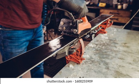 Applying Ski Wax To Ski Base with iron. Ski base tuning and paraffin bars. skiing service repair. repairman in workshop ski service. Man Waxing In Workshop. - Shutterstock ID 1600255909