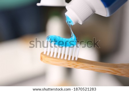 Applying toothpaste on brush against blurred background, closeup